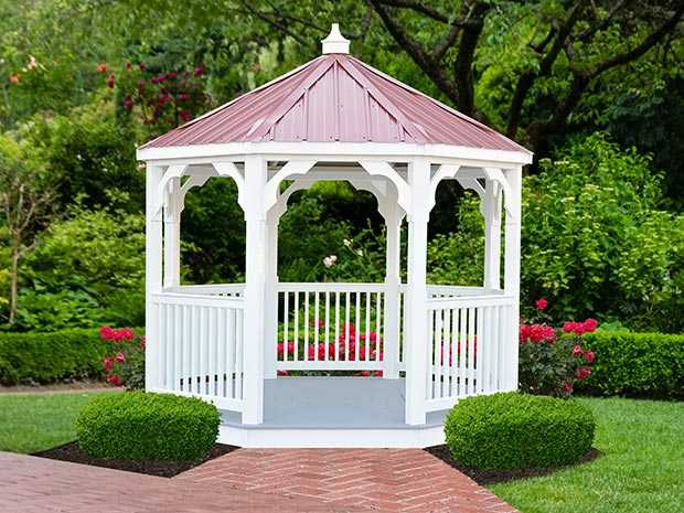 a White vinyl value gazebo with a burgundy roof surrounded by beautiful landscaping