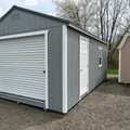 12x24 Classic Wood Garage. Gray Walls White Trim Slate Gray Roof. Options Include 8x7 Roll-up Door, Solid Panel Walk in Door, 1 - Window and Foil on Roof.