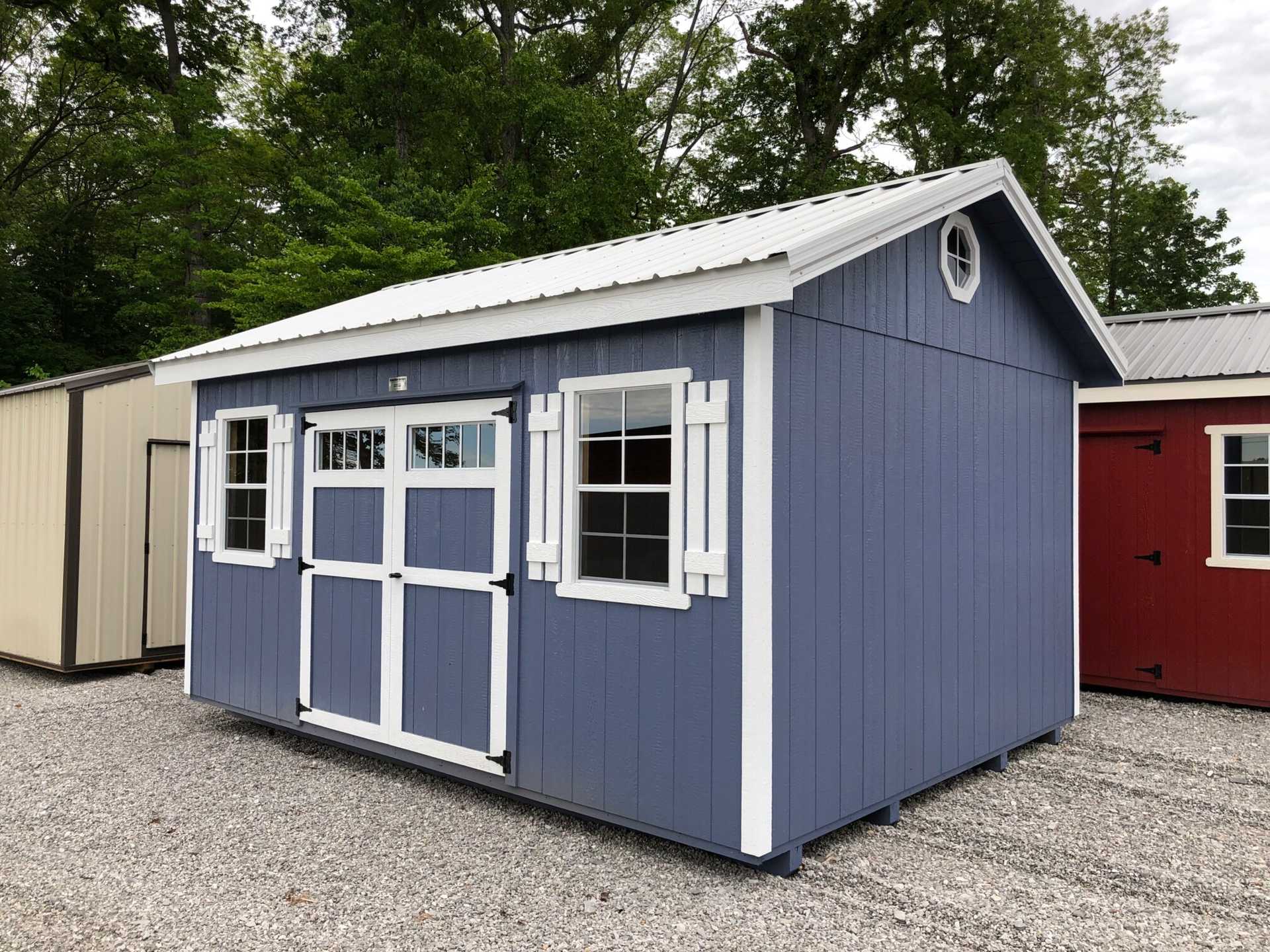 12x16 Deluxe Utility Shed painted Distance Blue with White trim around door, shutters, windows, and octagon windows. White metal roof