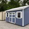 12x16 Deluxe Utility Shed painted Distance Blue with White trim around door, shutters, windows, and octagon windows. White metal roof