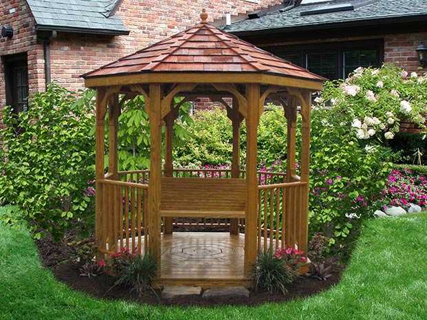 a Wood Gazebo with a swing and cedar shakes on the roof with landscaping around it