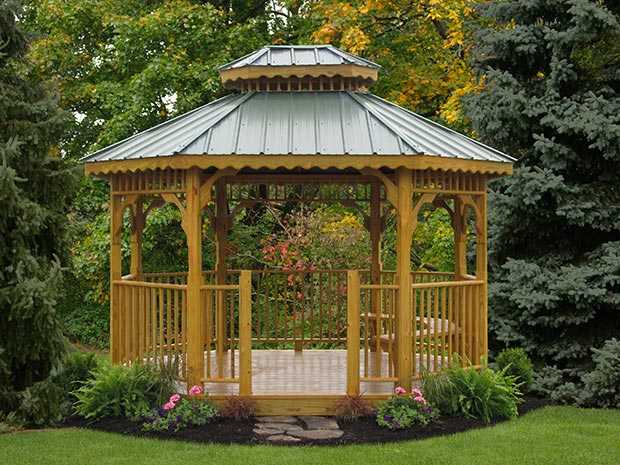 A Wood Octagonal Gazebo with a Green Double Roof set in some trees